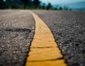 Asphalt highway with yellow line detail on road background